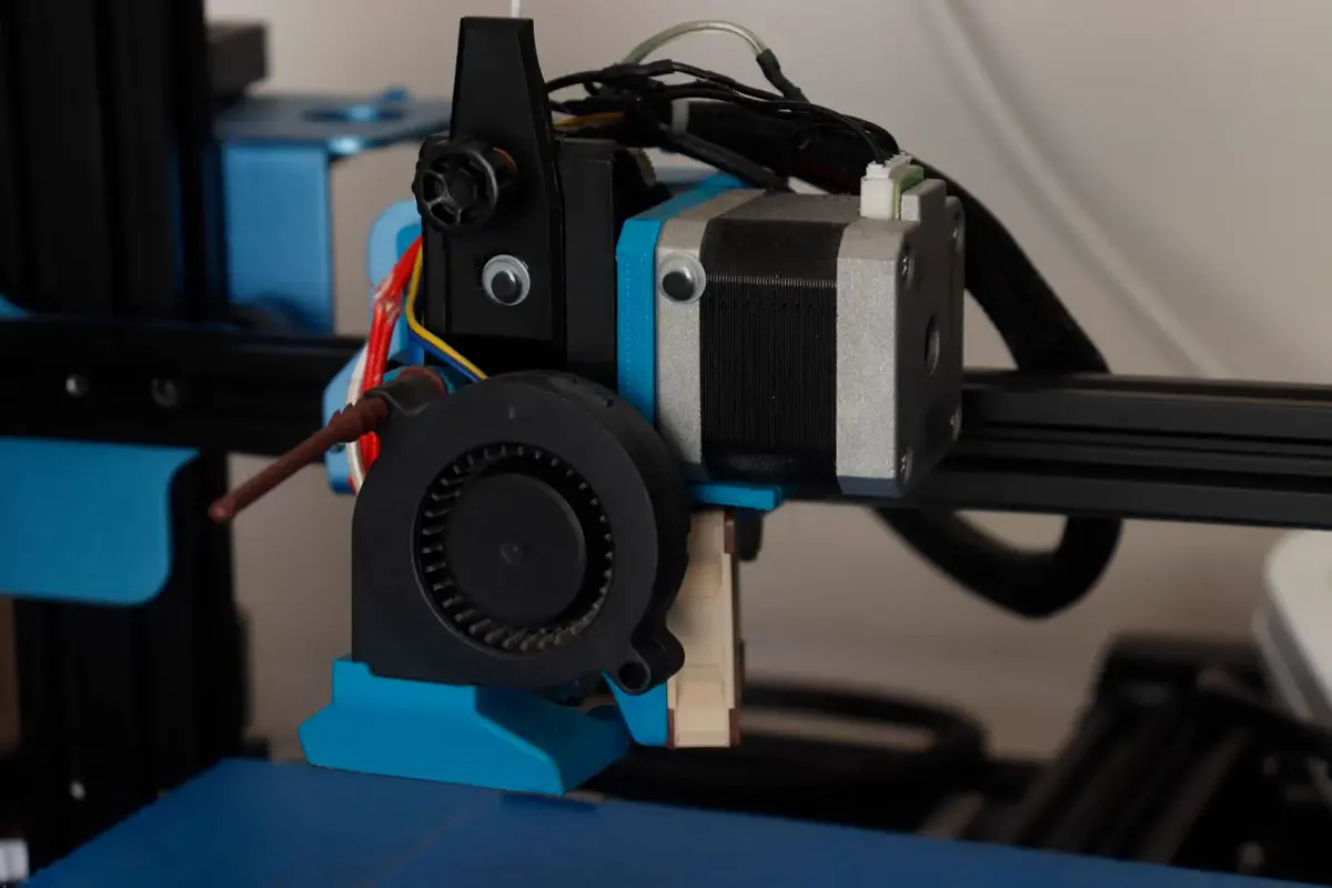 Extrudeur et ventilateur d’une imprimante 3D à filament, monté sur un portique noir et bleu