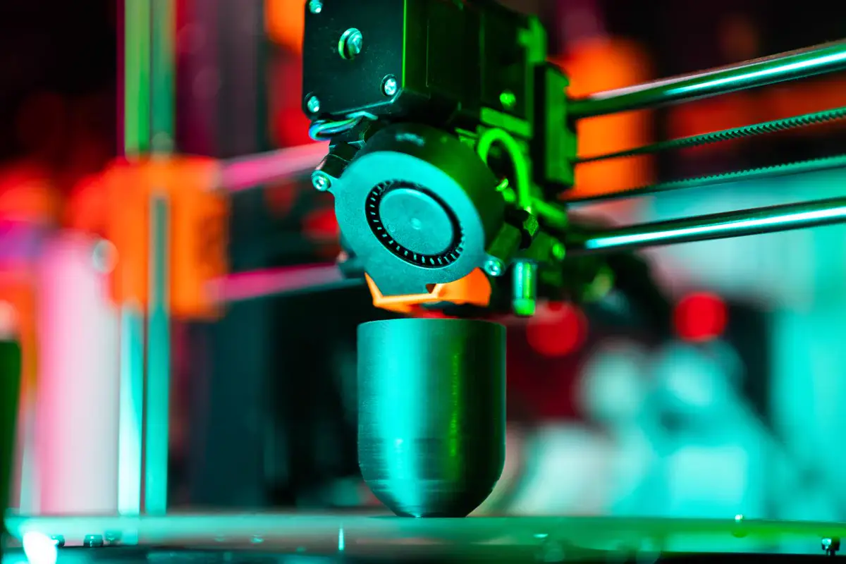 Gros plan sur la buse d’une imprimante 3D qui dépose les couches d’une pièce arrondie