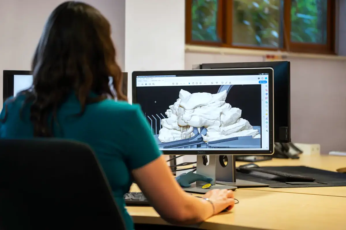 Personne vue de dos qui modélise une forme en 3D sur un écran d’ordinateur